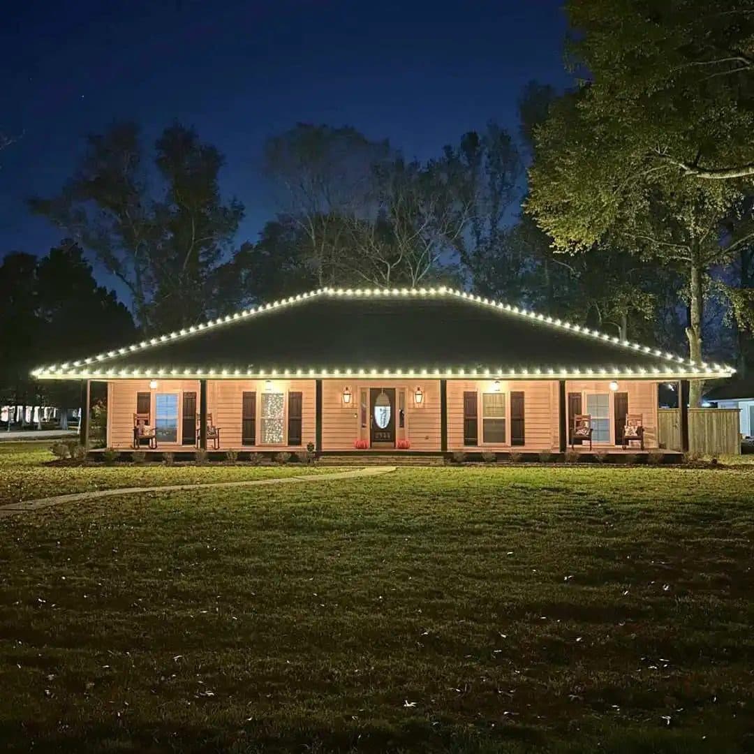 Warm white Christmas lights along the full roofline of a Baton Rouge brick home, installed by Hernandez Lawnscape