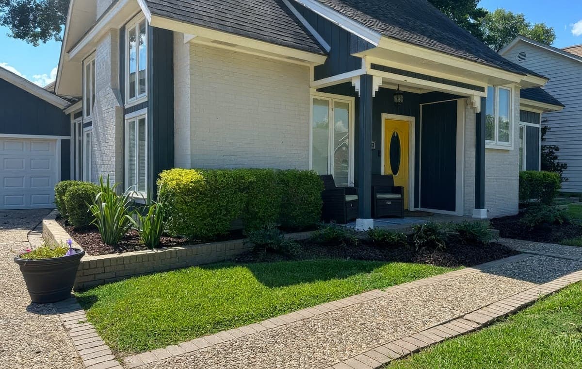 A well-kept home with a manicured lawn and trimmed shrubs along a stone walkway