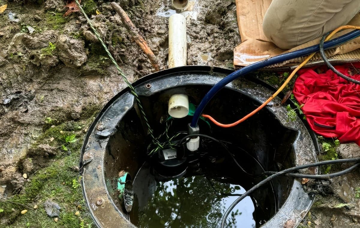 An open irrigation pit with a pump and supply lines during a repair