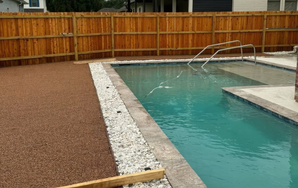 A new backyard pool with stone coping and white river rock edging