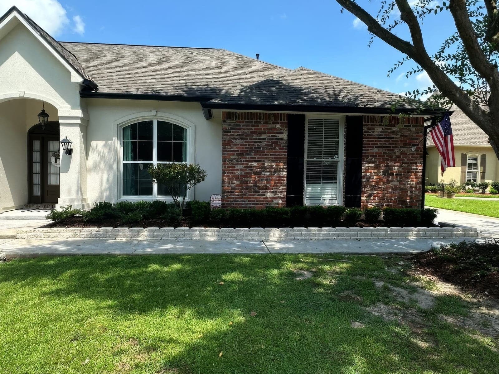 A front yard bed with freshly mulched, trimmed shrubs and a white stone border