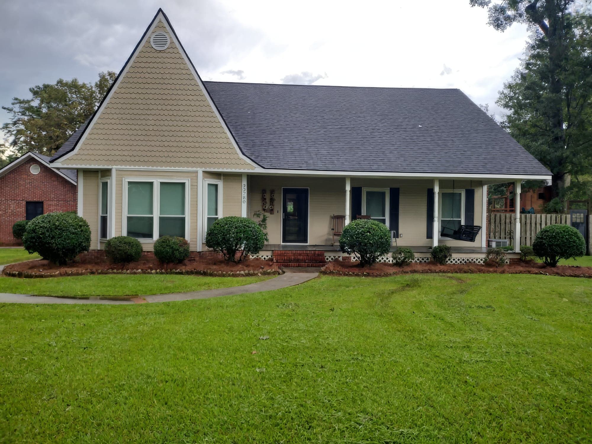 A single-story home with tan siding and a freshly mowed front yard