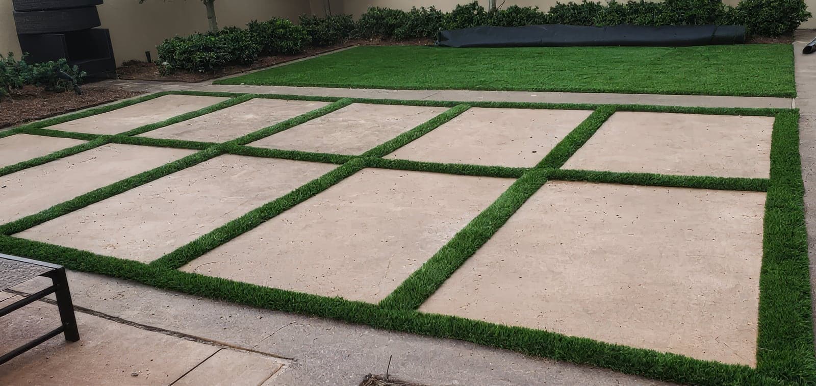 Large concrete patio pavers separated by strips of artificial turf