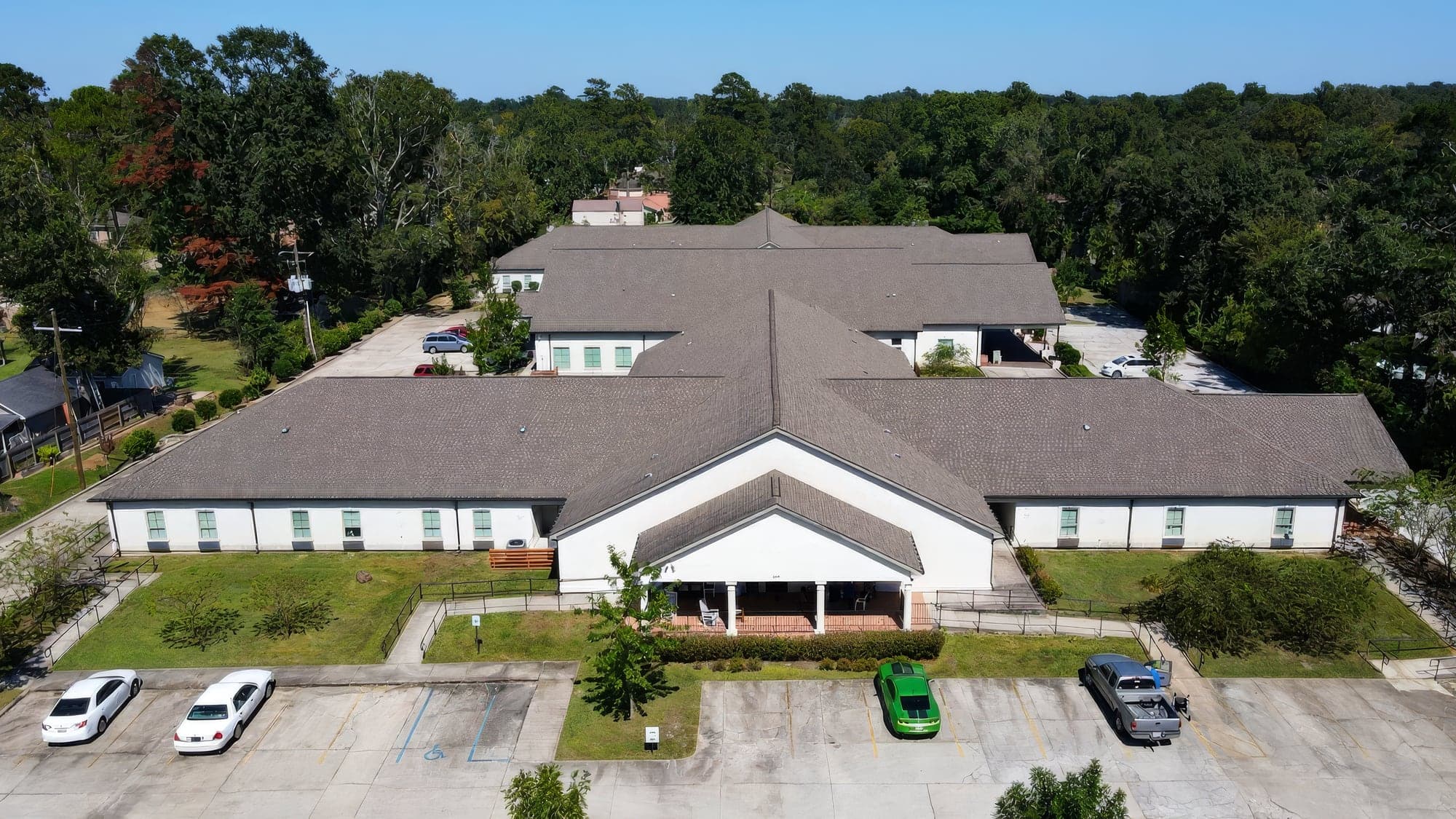 Aerial view of a church campus with mowed grounds, parking and a tree line, maintained by Hernandez Lawnscape