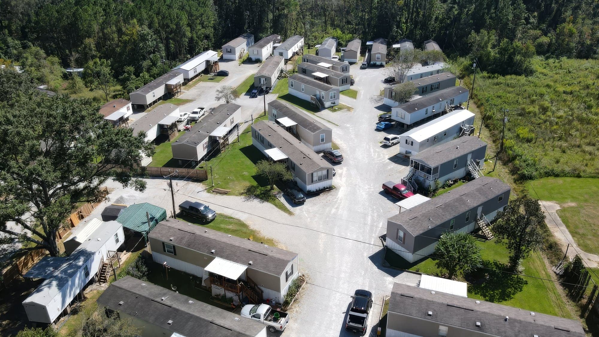 Aerial view of a manufactured-home community with maintained lawns and gravel drives