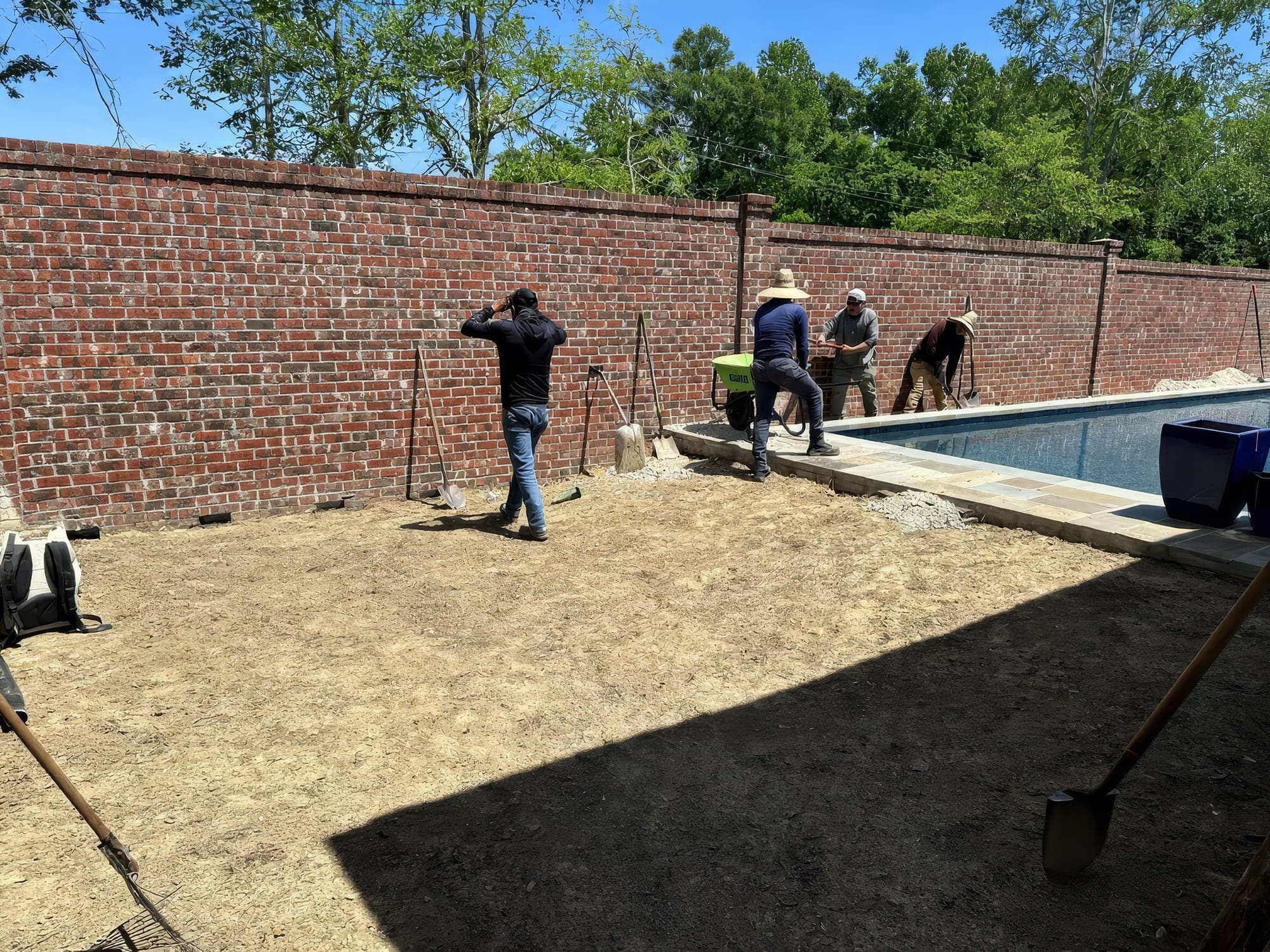 The crew grading a backyard beside a new pool before turf