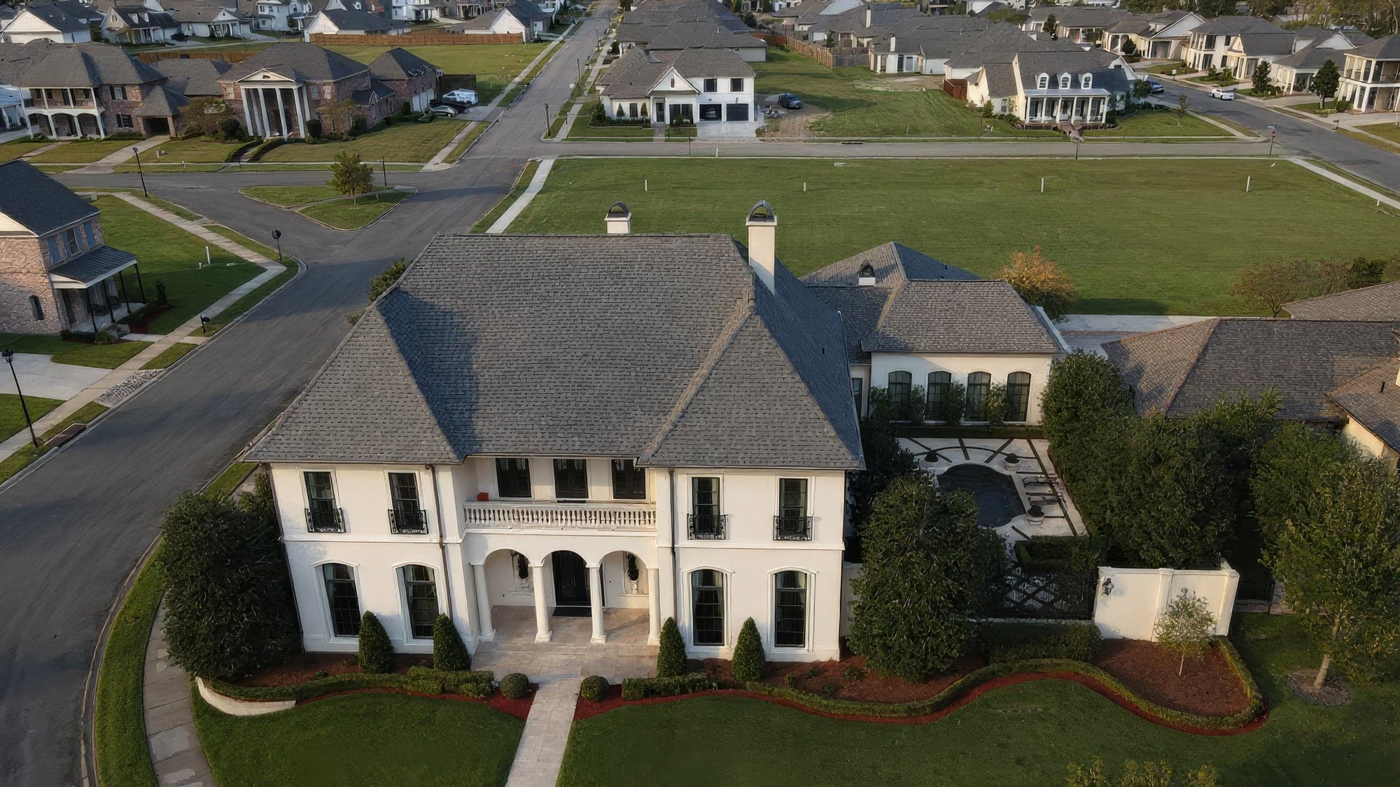 Aerial view of a white two-story estate home with new front beds