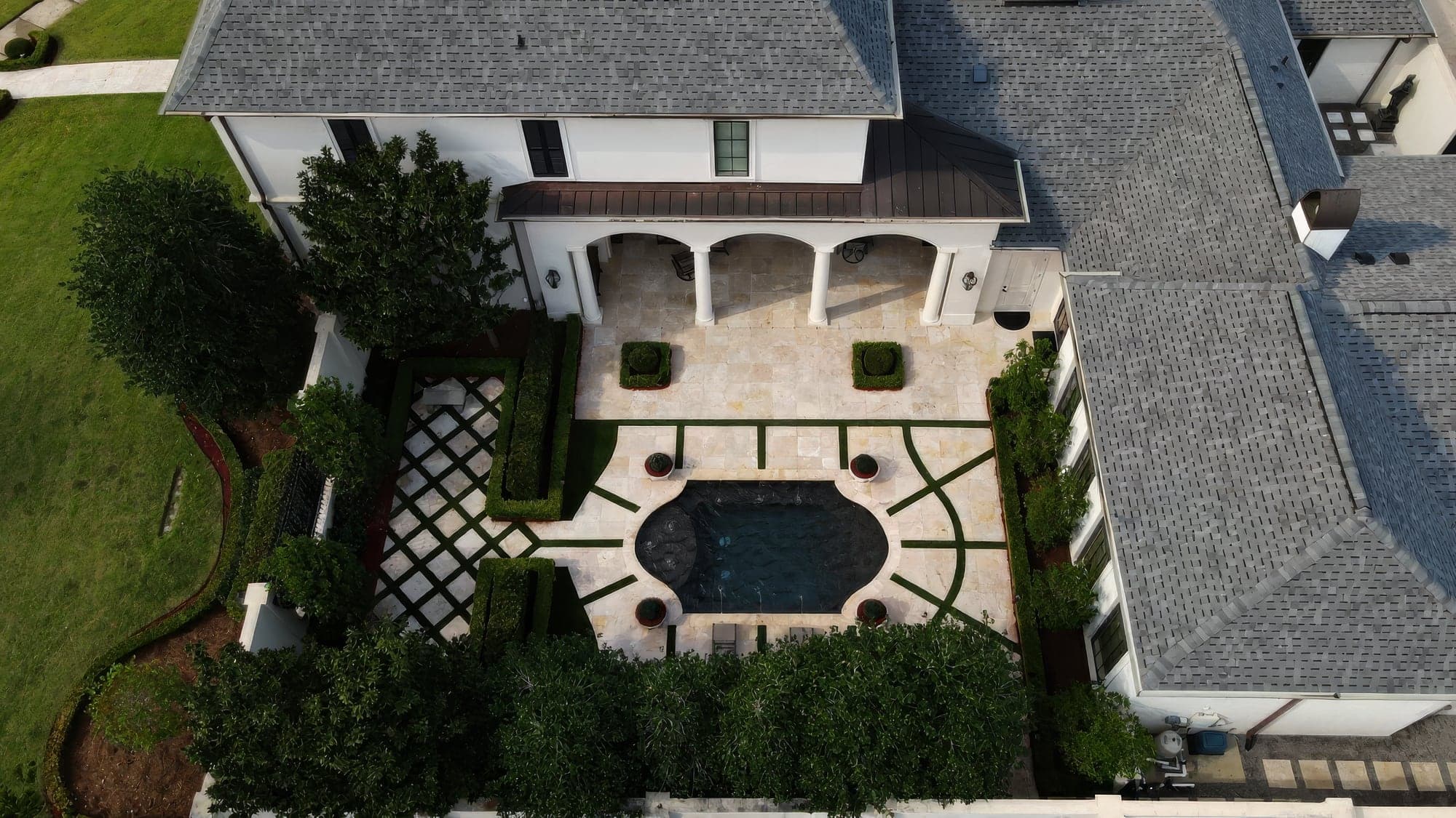 Aerial view of a formal courtyard with clipped hedges, turf inlays and a small pool