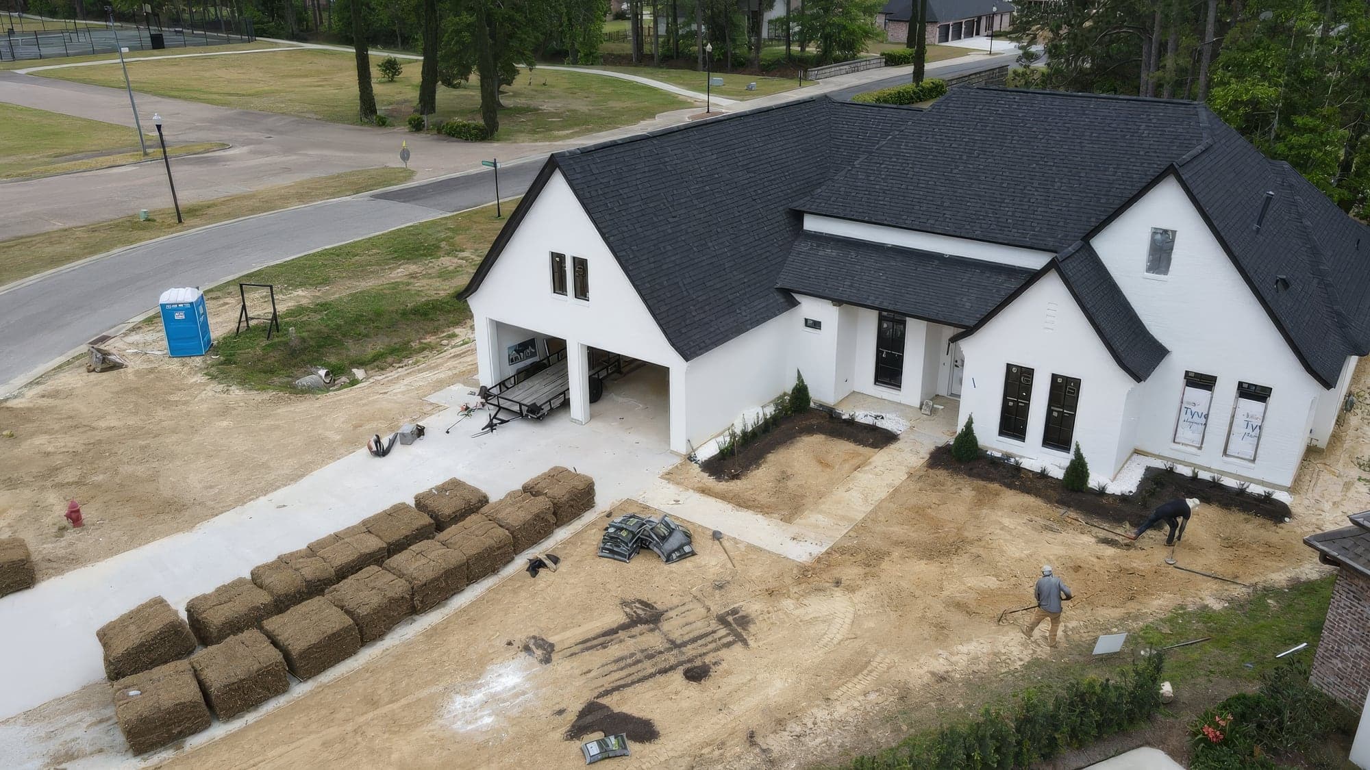 Aerial view of sod pallets staged at a new white farmhouse