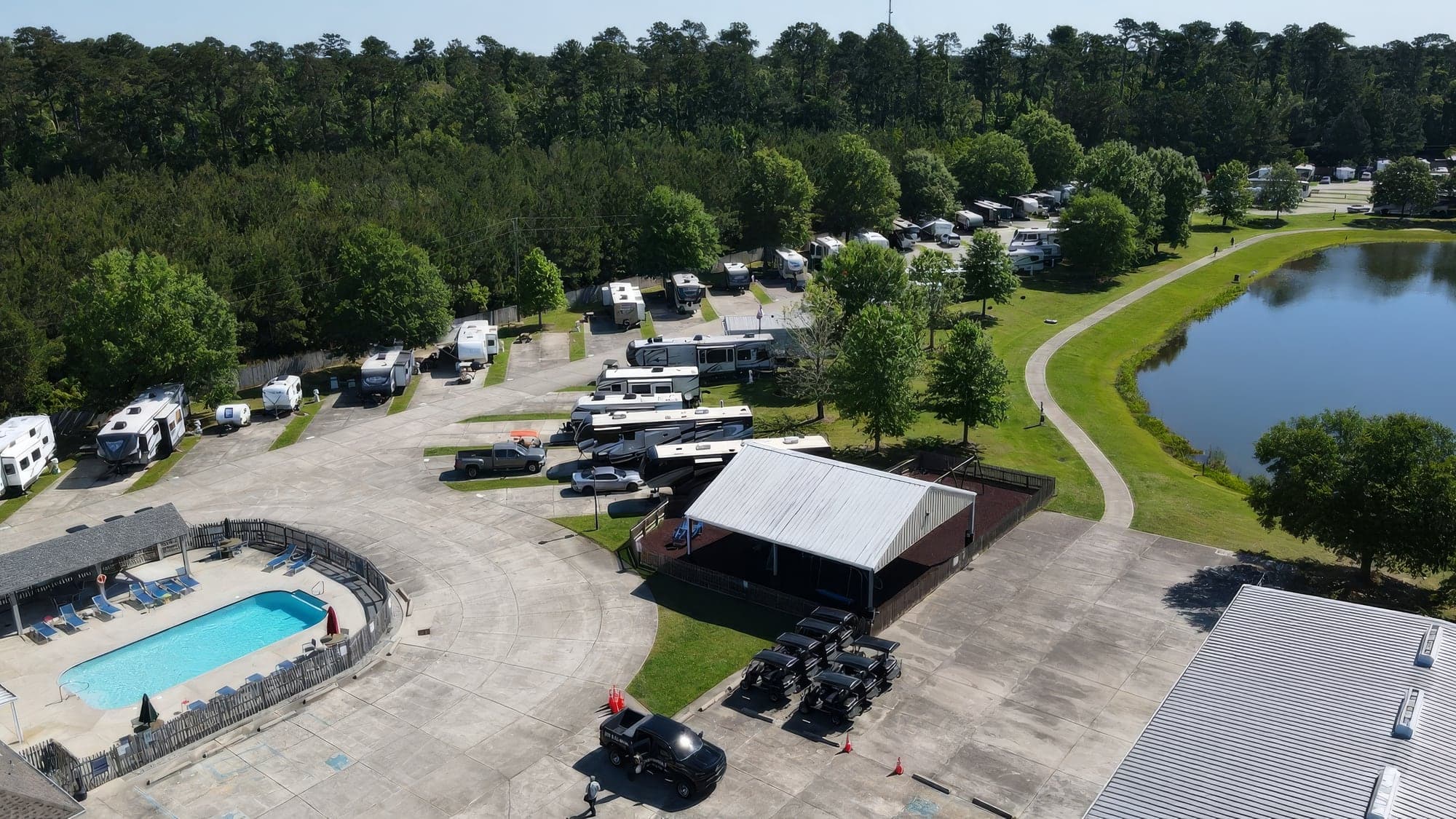 Aerial view of an RV park with a pool, pavilion and lakeside lawns
