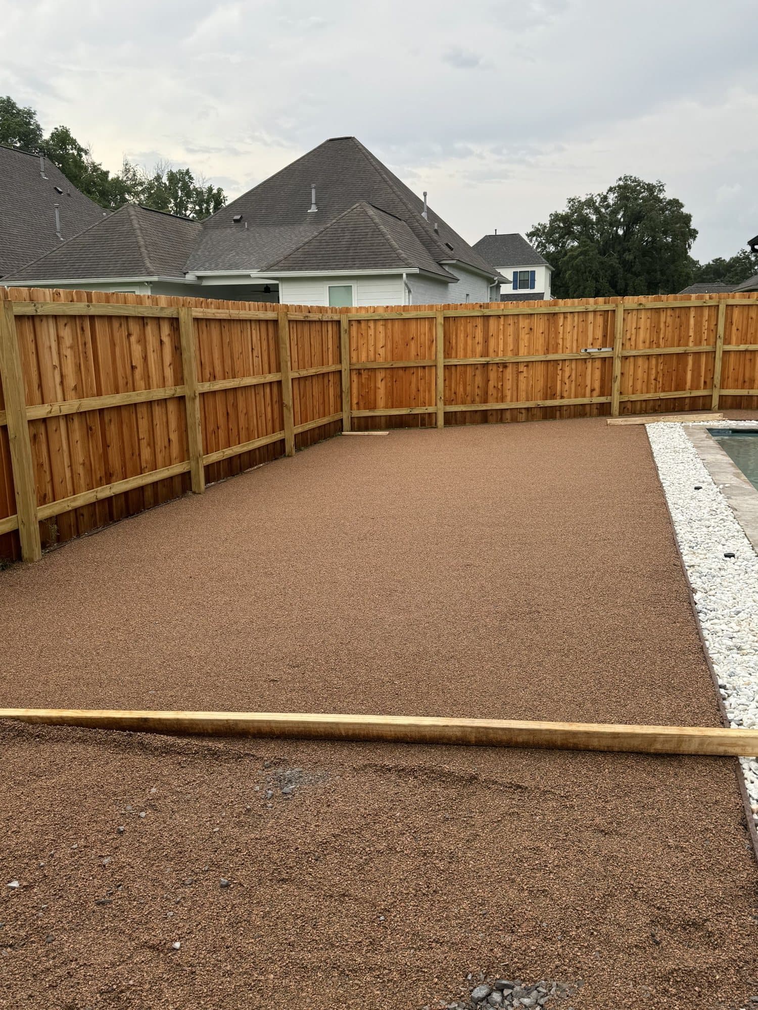 A compacted base being prepared for artificial turf beside a pool