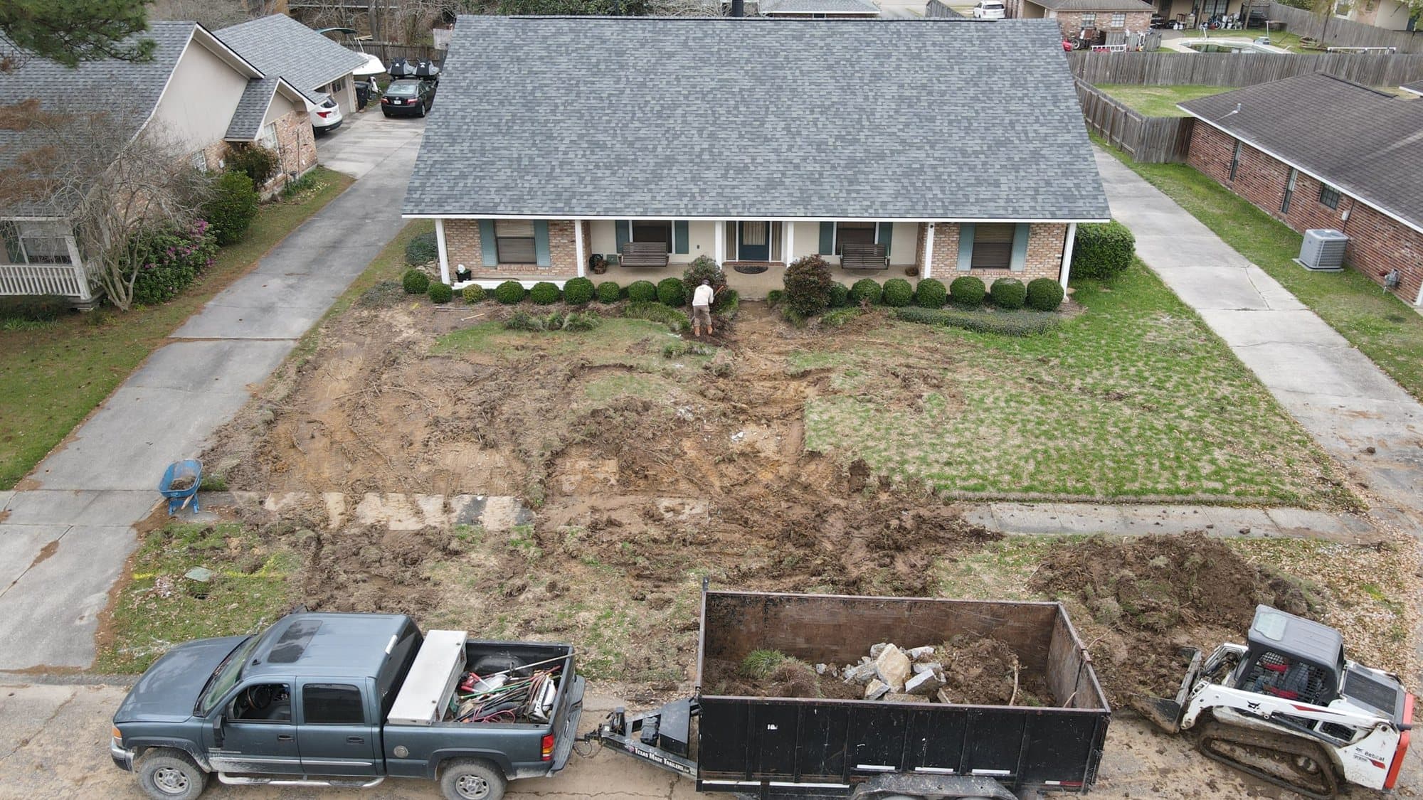 Aerial view of a front yard stripped to soil with a truck and trailer during a sod replacement
