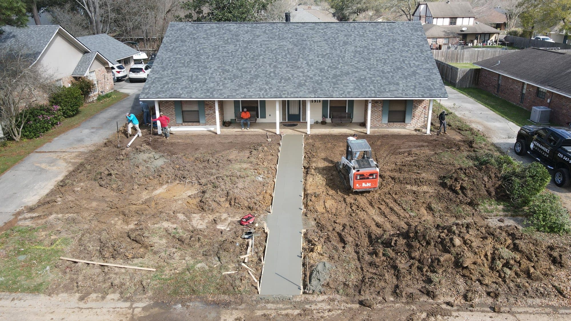 Aerial view of a compact loader grading a front yard for sod