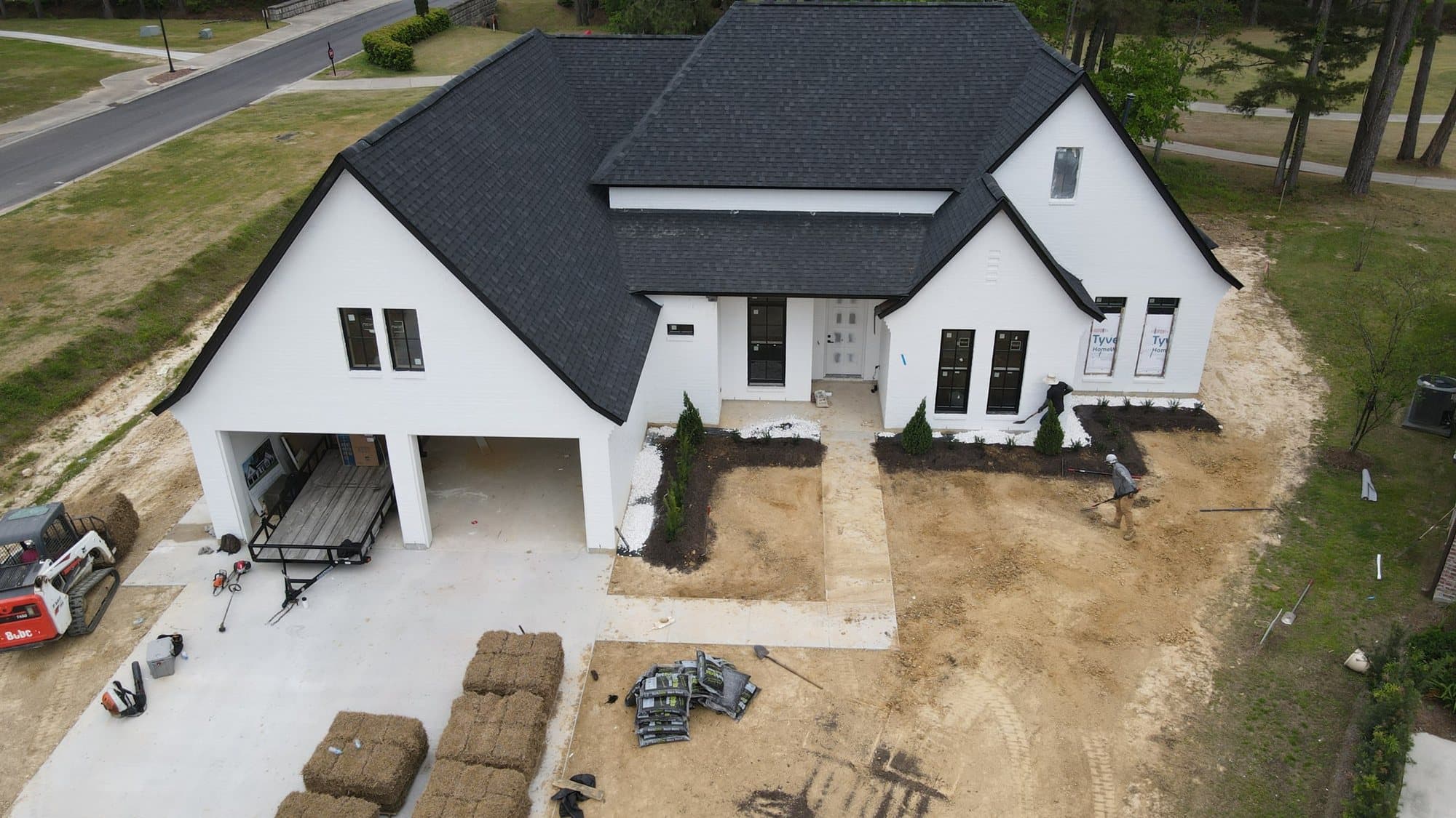 Sod pallets staged beside a new white farmhouse