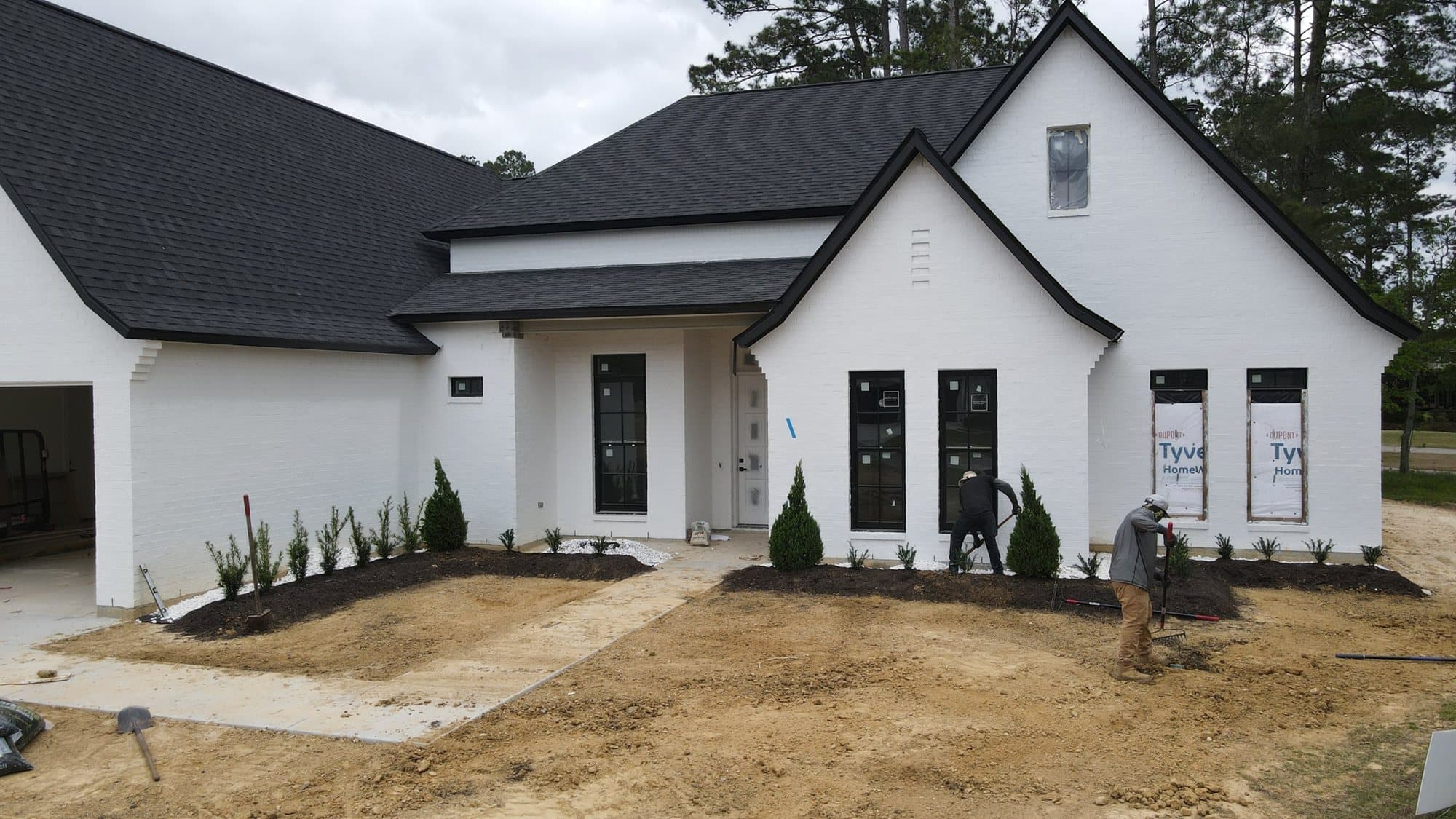 New beds planted along the front of a new white farmhouse
